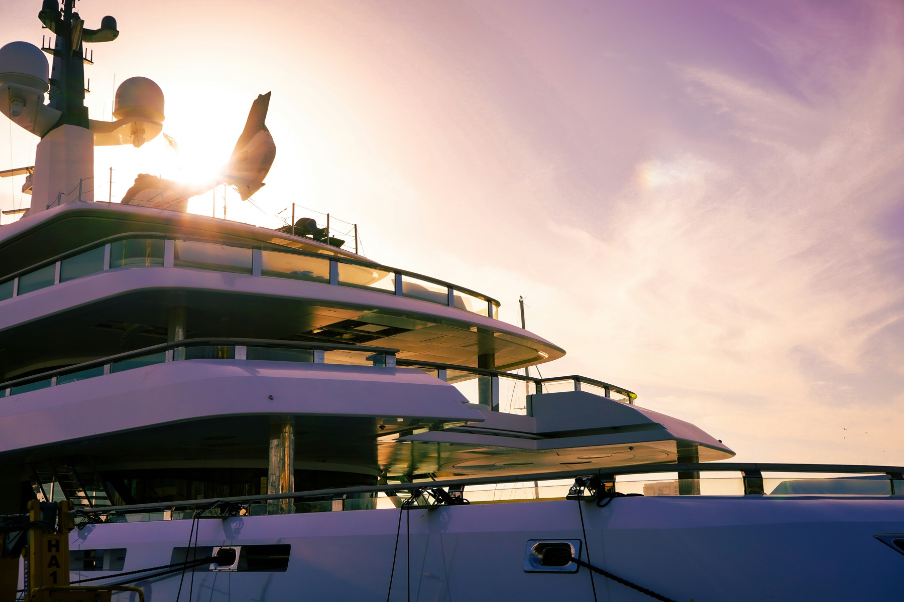 Large yacht deck at sunset with crew silhouette